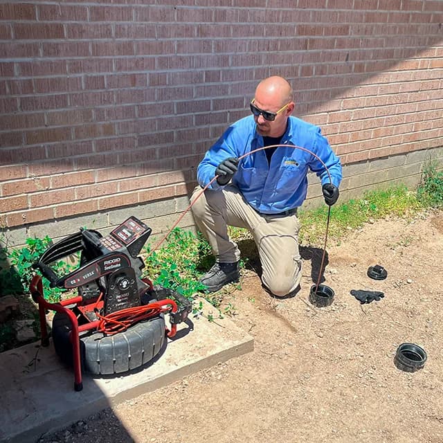 Plumber Kings technician running a drain camera inspection at a Tucson property