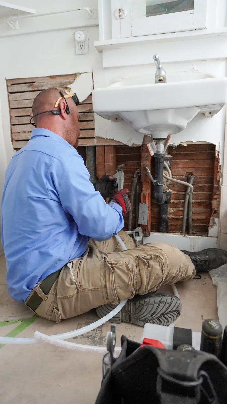 Technician repiping supply lines under a bathroom vanity