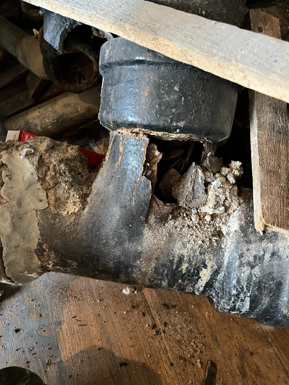 Rotted cast iron closet bend under a Tucson bathroom floor, cracked through at the joint