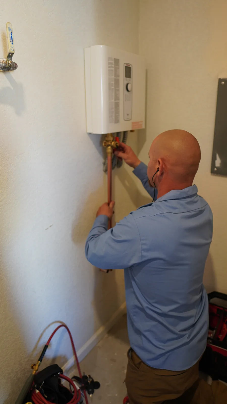 Technician installing a tankless water heater in a Tucson home