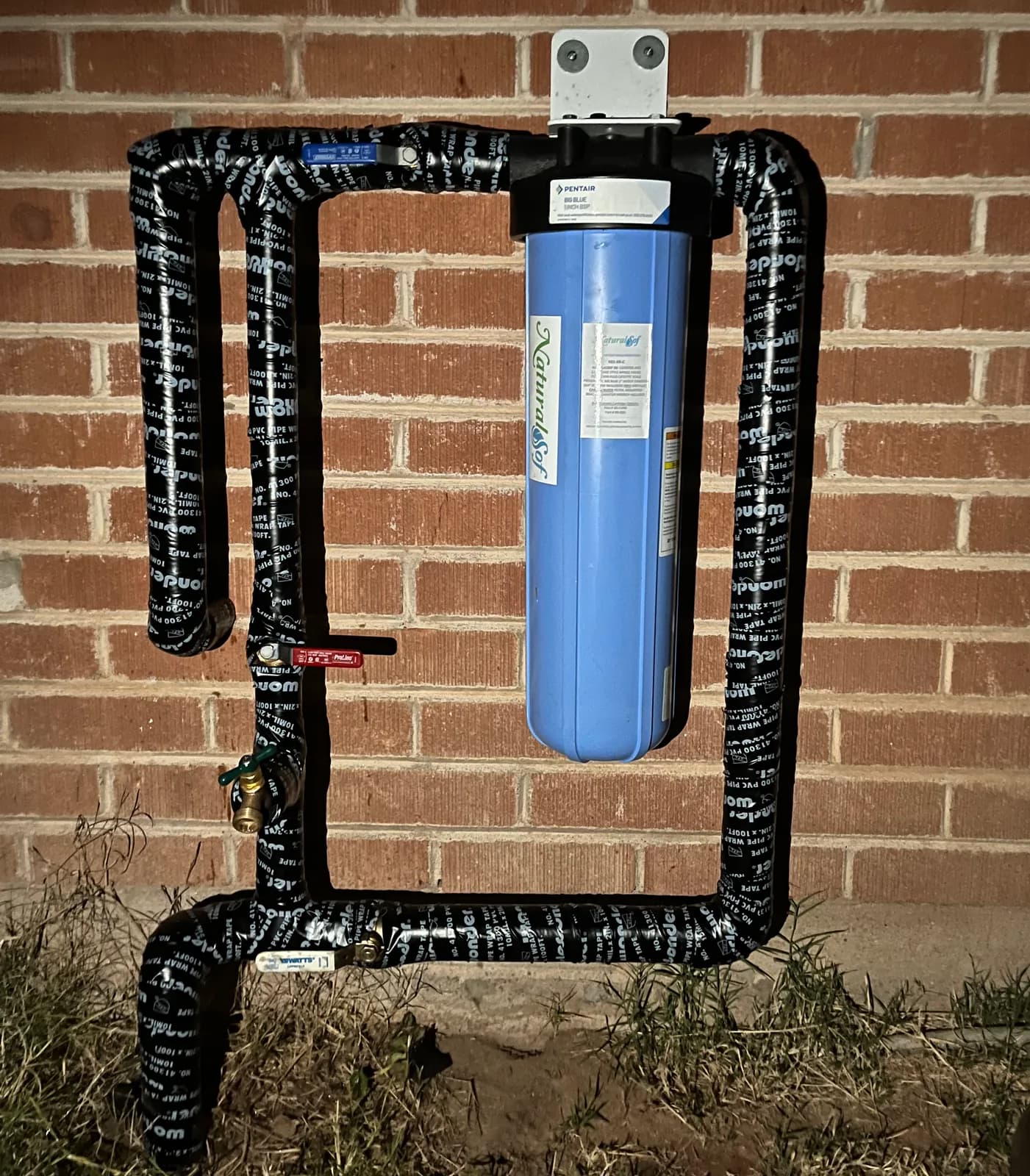 Whole-home water filtration system installed on an exterior wall